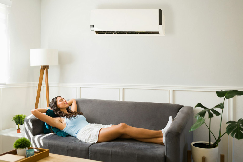Young woman on couch enjoying cool air.